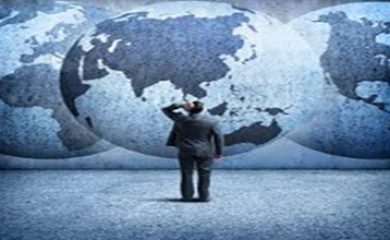 A rear view of a businessman as he stands and looks up at three interlocking globes on the wall in front of him as he tries to sort out the mess of geopolitical events. A globe rotated to Asia is in the center. Map source material courtesy of https://images.nasa.gov/